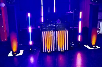 Installation de matériel de sonorisation et éclairage coloré dans une salle sombre, avec une table centrale.
