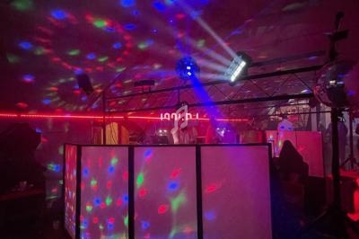 Je ne sais pas qui est sur cette image, mais voici une description : Salle sombre avec jeux de lumières colorées, cabine de…