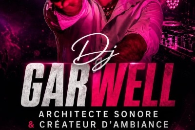 Un DJ en chemise rouge et lunettes de soleil mixe sur une scène avec éclairage rose et ambiance festive.
