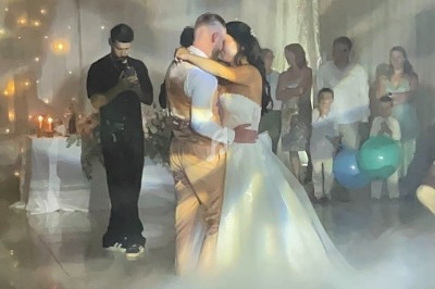 Un couple danse leur première danse de mariage dans une salle décorée avec des lumières et des drapés.