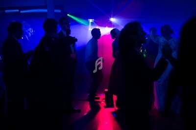 Des personnes dansent dans une salle sombre éclairée par des lumières colorées bleues et rouges.