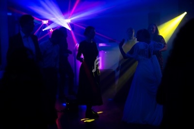 Des personnes dansent sous des lumières colorées dans une ambiance festive et tamisée.