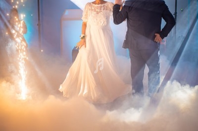 Un couple danse au milieu de la fumée et des lumières, avec des étincelles en arrière-plan.