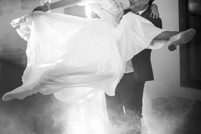 Un couple danse, l'homme portant la femme en robe blanche, dans une ambiance éclairée par des effets de fumée.