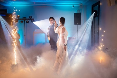 Un couple danse dans une ambiance festive avec des lumières colorées, des projecteurs et des effets de fumée.