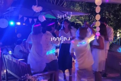 Des personnes dansent en soirée sous des lumières colorées, entourées de décorations festives en extérieur.