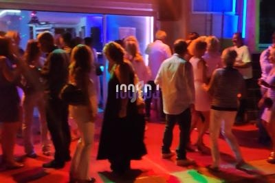 Personnes dansant et discutant dans une ambiance festive avec éclairage coloré en soirée.