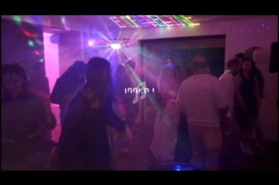 Des personnes dansent sous des lumières colorées dans une ambiance festive en intérieur.