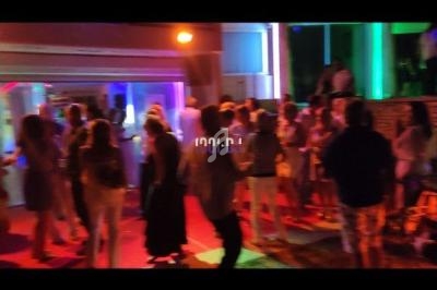 Personnes dansant et discutant dans un espace extérieur éclairé par des lumières colorées en soirée.