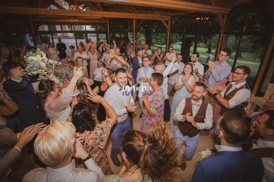 Des invités dansent et célèbrent lors d'une réception de mariage dans une salle lumineuse avec vue sur l'extérieur.