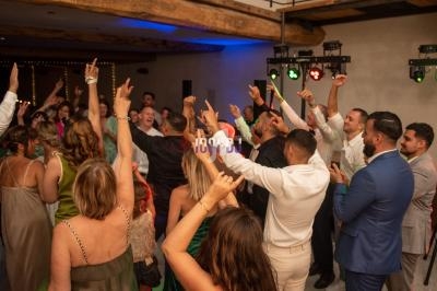 Groupe de personnes dansant et levant les bras lors d'une fête dans une salle éclairée.