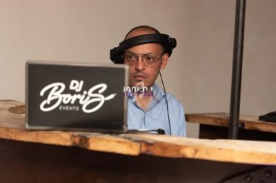 Un homme portant un casque audio se tient derrière un ordinateur portable sur une table en bois.