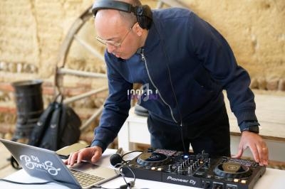 Un DJ portant un casque ajuste des réglages sur une table de mixage devant un ordinateur portable.