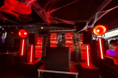 Scène de concert avec éclairage rouge intense, décorations de toiles d'araignée et matériel audio sur une estrade.