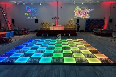 Piste de danse lumineuse multicolore dans une salle décorée avec des tables, des chaises et des éléments dorés.