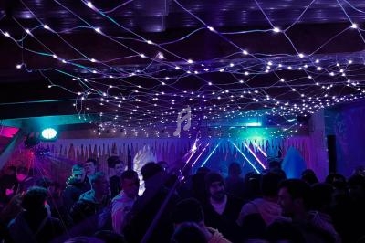 Groupe de personnes rassemblées dans un espace sombre décoré de guirlandes lumineuses violettes.