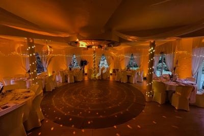 Salle de réception décorée avec des guirlandes lumineuses, tables dressées et ambiance chaleureuse.