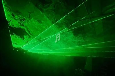 Effets de faisceaux laser verts projetés dans une pièce sombre avec une légère fumée visible.