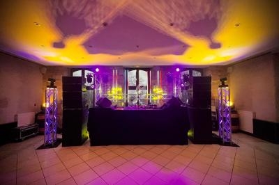 Installation de matériel de sonorisation et éclairage avec projecteurs violets et jaunes dans une salle vide.