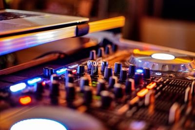 Table de mixage avec boutons, curseurs et éclairages colorés, utilisée pour des performances musicales ou DJ.