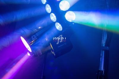 Projecteur lumineux diffusant des faisceaux colorés dans un environnement sombre.