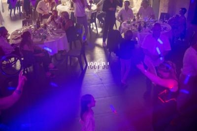 Des invités dansent sous des lumières colorées lors d'une réception avec des tables dressées en arrière-plan.