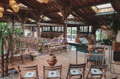 Salle en bois avec des chaises disposées pour un événement, éclairée par des lanternes et des puits de lumière.