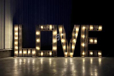 Lettres lumineuses formant le mot ’LOVE’ posées sur un sol en béton dans un environnement sombre.