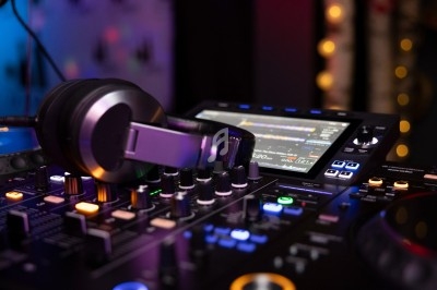 Table de mixage avec casque audio posé dessus, entourée de lumières colorées dans un environnement sombre.