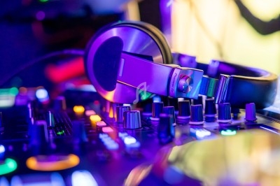Casque audio posé sur une table de mixage éclairée par des lumières colorées dans un environnement sombre.