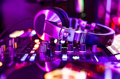 Casque audio posé sur une table de mixage entourée de lumières colorées dans un environnement sombre.