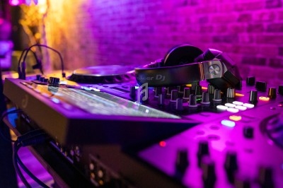Table de mixage avec casque audio posé dessus, éclairée par des lumières violettes dans un environnement sombre.