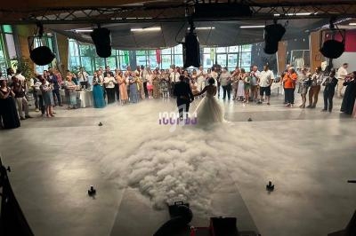 Un couple danse au centre d'une salle entourée d'invités, avec un effet de fumée au sol.