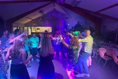 Groupe de personnes dansant dans une salle éclairée par des lumières colorées lors d'une fête.