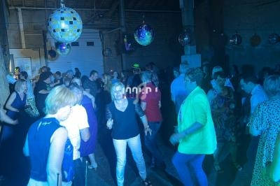 Des personnes dansent dans une salle sombre éclairée par des lumières colorées et des boules à facettes.