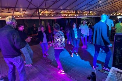 Des personnes dansent sur une piste éclairée par des lumières colorées sous une structure couverte.