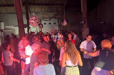 Groupe de personnes dansant et discutant dans une salle avec des lumières colorées et des boules à facettes suspendues.