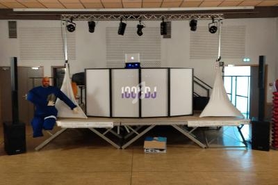 Scène de DJ avec éclairage suspendu, table de mixage et décorations rouges en forme de cœur.