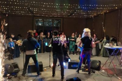 Groupe de musiciens jouant sur scène devant un public, entourés de lumières et d'effets pyrotechniques.