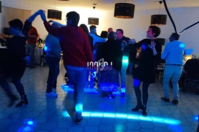 Des personnes dansent sur une piste éclairée de lumières bleues lors d'une soirée festive en intérieur.