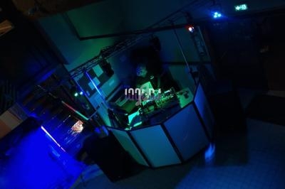 Vue d'une cabine de DJ éclairée par des lumières colorées dans une ambiance sombre.