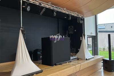 Scène intérieure avec matériel de sonorisation, éclairage suspendu et décoration minimaliste.