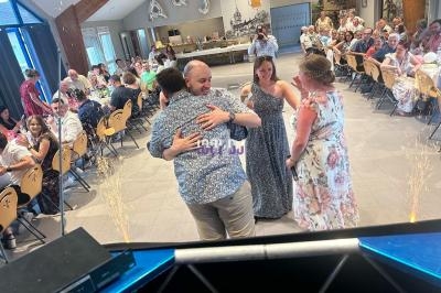 Un homme et une femme s'enlacent sur une piste de danse lors d'une réception avec des invités assis en arrière-plan.