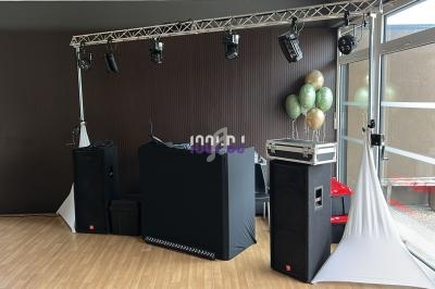 Installation de matériel de sonorisation et d'éclairage dans une salle avec des ballons décoratifs en arrière-plan.