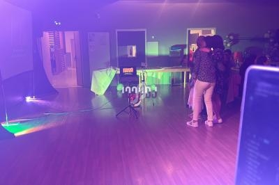 Des personnes discutent dans une salle éclairée par des lumières colorées, avec des tables et des équipements en arrière…