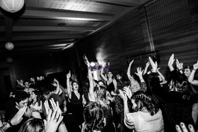 Groupe de personnes dansant et levant les bras lors d'une fête dans une salle sombre.