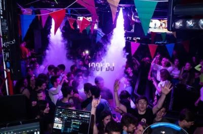 Foule dans une discothèque avec éclairages colorés, fumée et décorations de fanions suspendus.