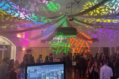 Salle décorée avec des lumières colorées projetées au plafond, avec des invités debout et un écran de contrôle au premier…