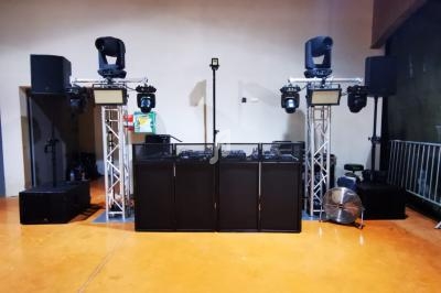 Installation de matériel de sonorisation et d'éclairage avec projecteurs et enceintes dans une salle au sol orangé.