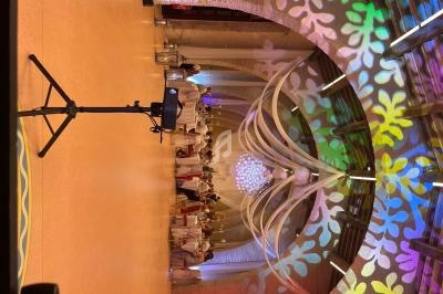 Salle décorée avec des lumières colorées et des motifs projetés, accueillant un groupe de personnes en tenue blanche.